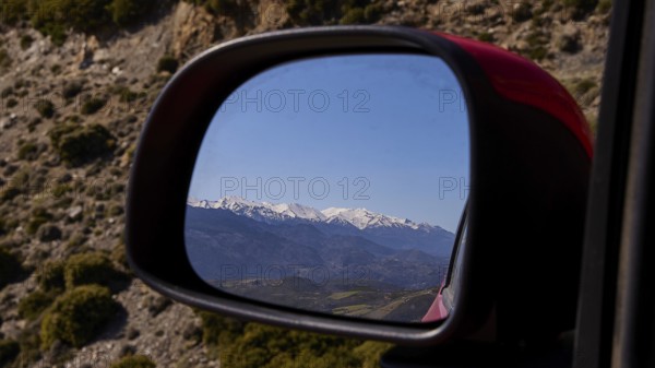 Mountain landscape in winter, reflected in the car mirror during a car journey, Lefka Ori, White