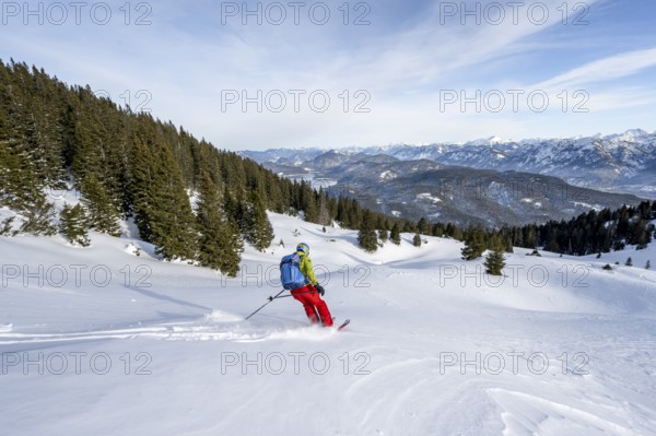Skiers skiing down the Simetsberg, view of Walchensee and mountain panorama, Estergebirge, Bavarian