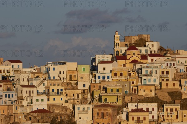 Cycladic architecture on a hill with a central church, warm light dominates the scene, Colourful