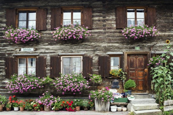 Old wooden house with geraniums in front of the windows in Zollstraße, Oberstdorf, Oberallgäu,