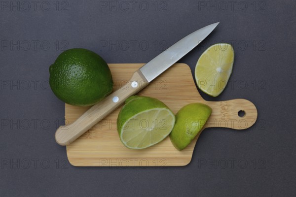 Halved limes on a chopping board with a kitchen knife