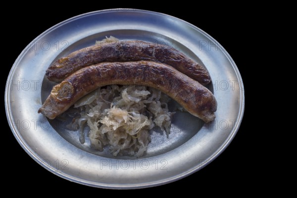 Pewter plate with two Franconian sausages and sauerkraut on a black background, Bavaria, Germany,