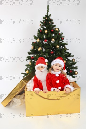 Children dressed up as Santa Claus, in big gift, on the Christmas tree, decorated Christmas tree,