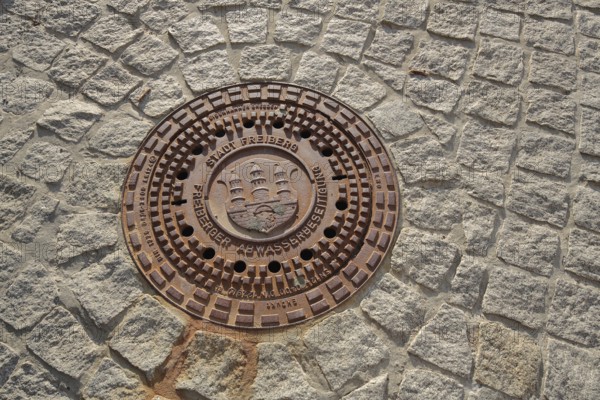 Manhole cover with city coat of arms, paving stones, soil, sewerage, Freiberg, Freiberg, Saxony,