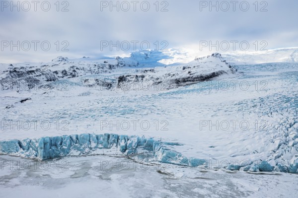 Snow-covered icebergs in the Fjallsarlon glacier lagoon, with the Öraefajökull glacier behind,