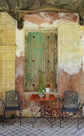 Table and chairs, seat in front of old door, Chania, Crete, Greece, Europe