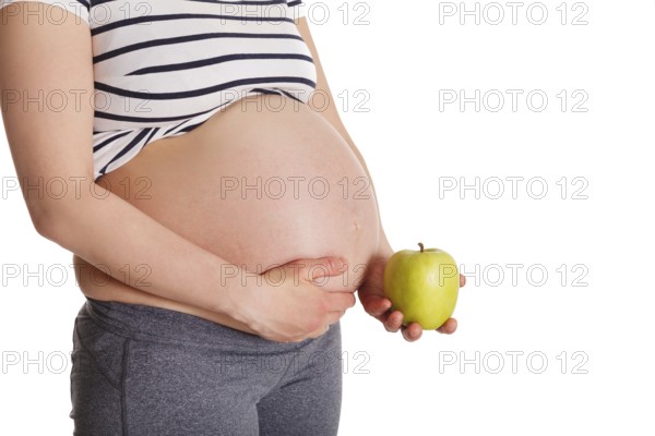 Healthy eating and diet during pregnancy concept, pregnant woman standing and holding green apple