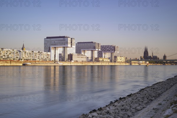 Crane houses in the Rheinau harbour and Cologne Cathedral seen across the Rhine from the bollard