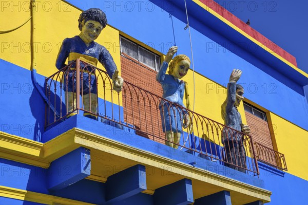 Footballer Diego Maradona, folk heroine Eva Perón and tango singer Carlos Gardel on a balcony,