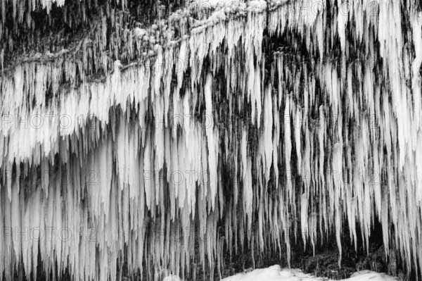 Icicles on the rock face at Skogafoss waterfall, black and white photo, Sudurland, Iceland, Europe