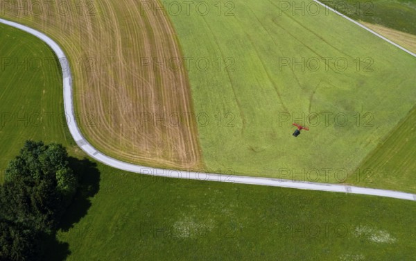 Drone view of a tractor turning hay in the field, Flachgau, Land Salzurg, Austria, Europe