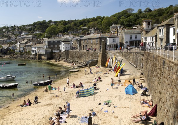 People on crowded beach in Mousehole village, Cornwall, England, UK