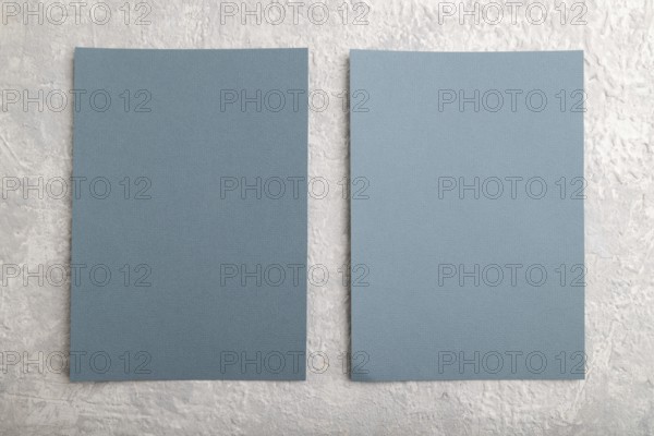 Blue paper business card, mockup on gray concrete background. Blank, flat lay, top view, still
