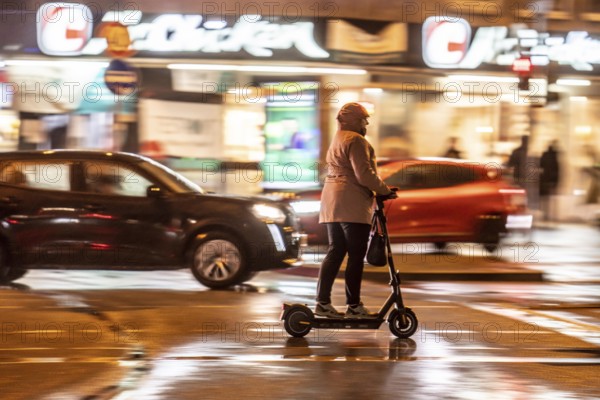 Street at the main station, e-scooter driver, rainy weather, city centre, in the evening, Essen,
