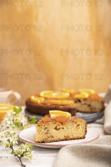 Orange cake and a cup of coffee on a white wooden background and linen textile. Side view, copy