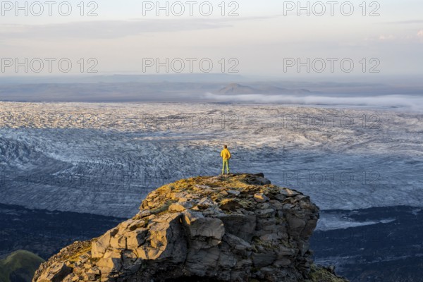 Young man, tourist in front of impressive glacier, in evening light, landscape with mountains and