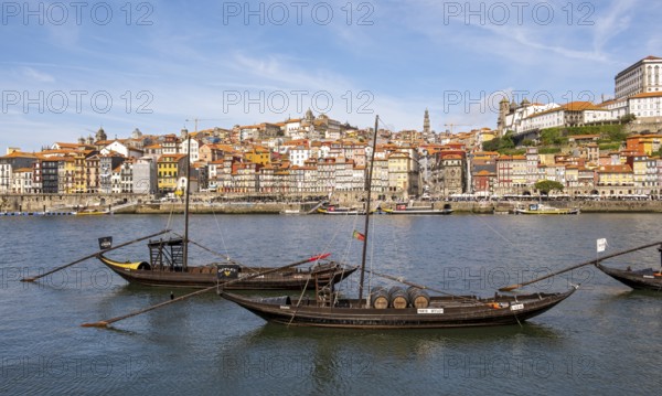 Old boats line the Douro River, with the charming Ribeira district in the background, Porto,