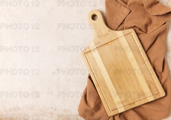Cutting board, beige, unpainted, with a kitchen towel, on a beige background, top view
