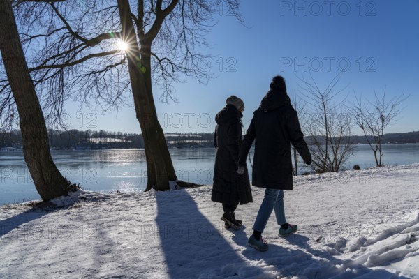 Winter in the Ruhr area, Lake Baldeney, snow-covered, partly frozen lake, walkers on the lakeside