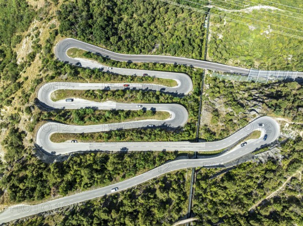 Mountain pass road with multiple hairpins, water pipeline, aerial view, drone shot. Valais,