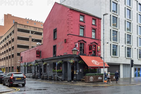 Red building on a street corner with urban flair, cars and a rainy atmosphere, Belfast