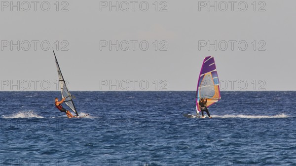 Two windsurfers navigating over the blue sea under clear skies, windsurfing, Meltemi windsurfing
