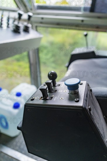 Control unit with a blue button and two levers in front of a window front, Hermann Hesse Bahn track