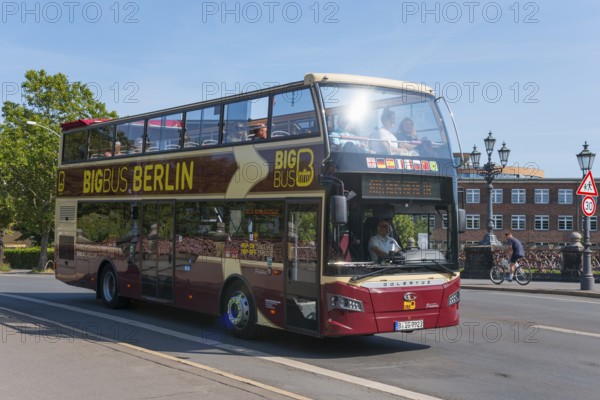 A red Berlin sightseeing double-decker bus on a street, full of tourists, double-decker bus,