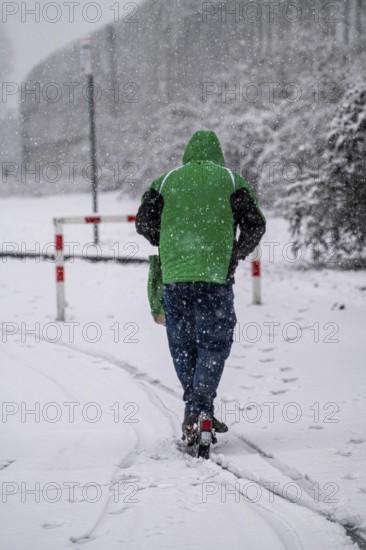 Winter weather, heavy snowfall, city centre traffic, man on e-scooter in driving snow, Essen, North