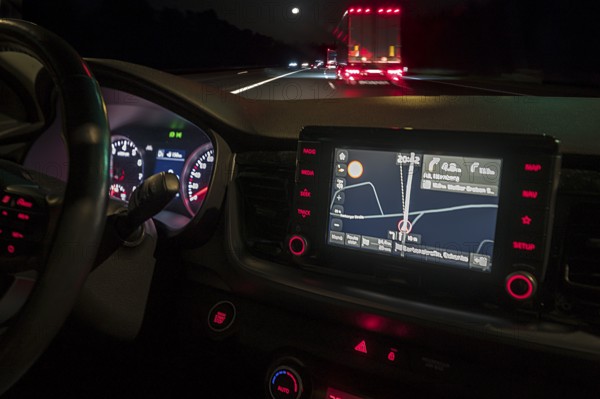 Nocturnal street scene with lorry, fromre an illuminated cockpit with sat nav of a car, Bavaria,