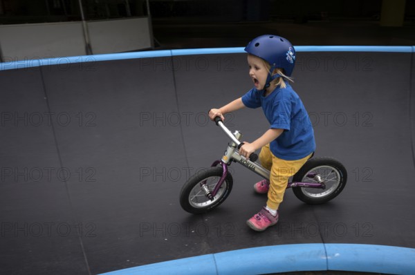 Little girl, 3 years, blonde, helmet, helmet, riding on balance bike, bicycle, skating rink,
