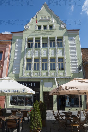Historic Art Nouveau building in pastel green with café on the ground floor under a blue sky, town