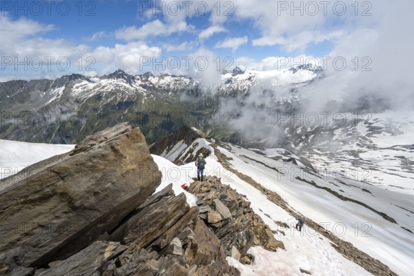Mountaineer on a rocky ridge with snow, descent from the summit of Schönbichler Horn, view of