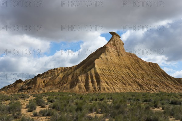 Lonely hilltop with characteristic shapes rises magnificently under a partly cloudy sky in the