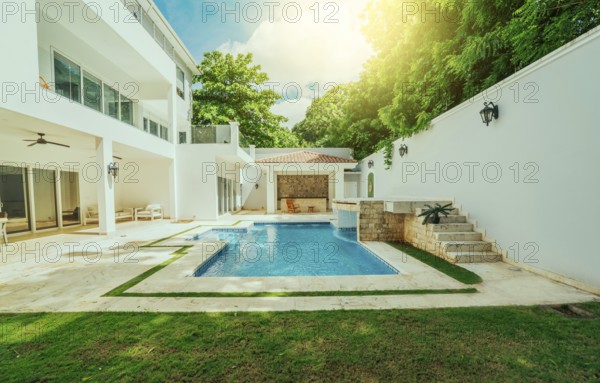 Beautiful crystal clear swimming pool in a backyard. Swimming pool surrounded by nature trees