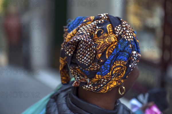 Colourful turban of a black immigrant woman in the old town of Genoa, Italy, Europe