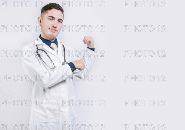 Doctor pointing back with his thumbs, recommending a product. Smiling latin doctor pointing back