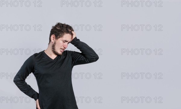 Worried man isolated. Worried young man holding his forehead. Tired man holding his head