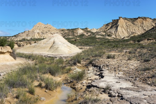 Dry desert landscape with hills and low-growing vegetation under a clear sky, Bardenas Reales