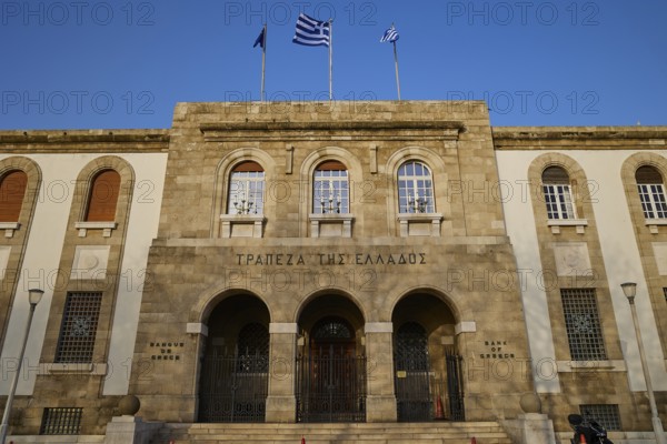 Greek Bank Building, Historic building with stone masonry and columns, decorated with Greek flags