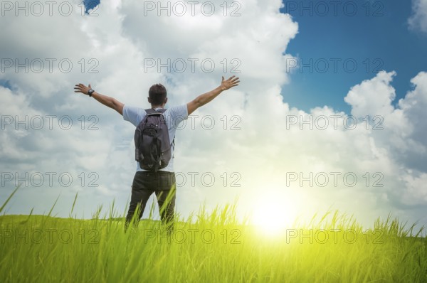 A backpacker on a hill with blue sky and copy space, man backpacking on a green hill with copy