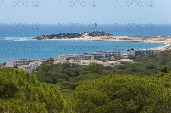 Island with lighthouse and white buildings, surrounded by green forest and blue sea, view of Los