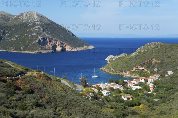 Small coastal village by the blue sea with surrounding green mountains and a peaceful atmosphere,
