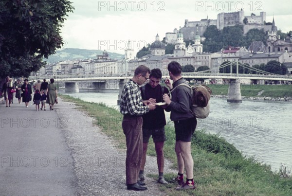 Two hitchhikers being helped with directions by a man, Salzach River riverbank, Salzburg, Austria