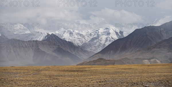 Glaciated, cloud-covered mountain peaks and golden meadows, Lenin Peak, Trans Alay Mountains, Pamir
