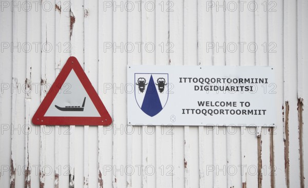 White wooden wall with a warning sign with a sledge symbol and a welcome sign Welcome to
