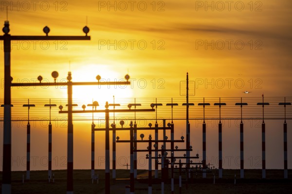 Runway lighting, approach aids, at Düsseldorf International Airport, sunset, aircraft approaching