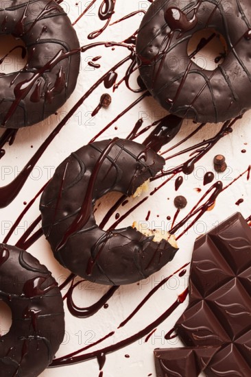 Donuts, in chocolate glaze, on a beige background, with liquid chocolate