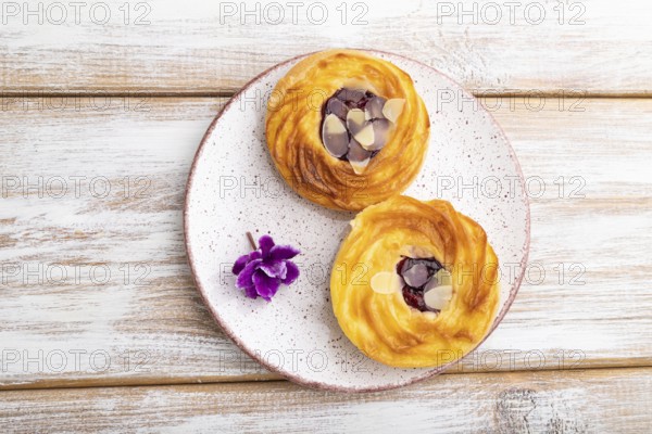 Small cheesecakes with jam and almonds on a white wooden background. top view, flat lay, close up