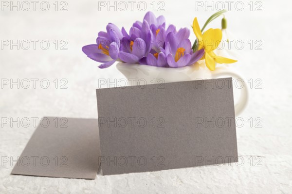 Gray paper business card mockup with spring snowdrop crocus and galanthus flowers on gray concrete